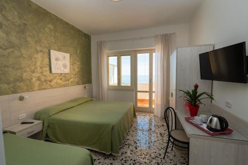 a hotel room with two beds and a television at Hotel Baia Verde in Maiori