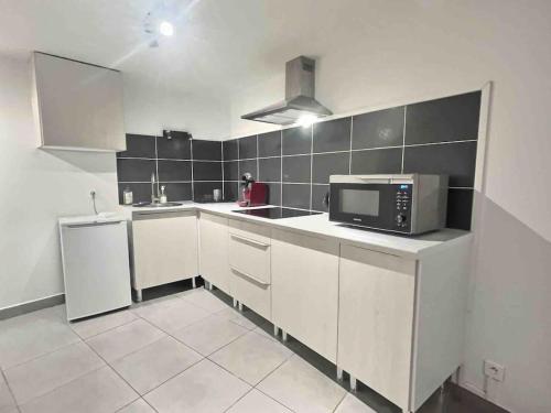 une cuisine avec des armoires blanches et un micro-ondes dans l'établissement Le Pélican Villardois - 2 chambres - centre, à Villars-les-Dombes
