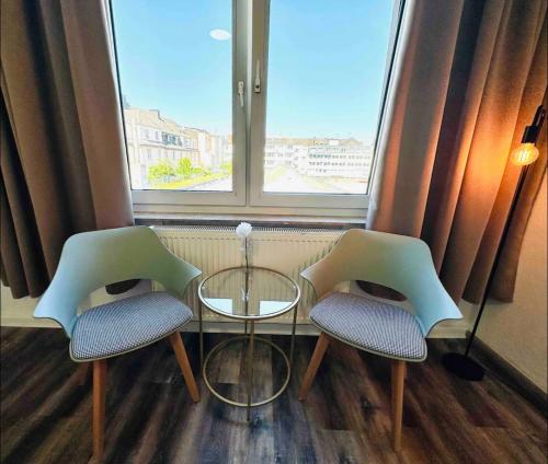 two chairs and a table in a room with a window at Zentral gelegenes und stilvoll möbliertes Apartment in Duisburg Nur 5 Minuten vom Hbf und City, ideal für Pendler und Messebesucher in Duisburg
