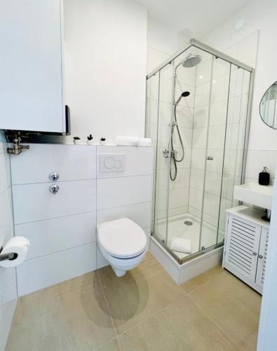 a white bathroom with a shower and a toilet at Zentral gelegenes und stilvoll möbliertes Apartment in Duisburg Nur 5 Minuten vom Hbf und City, ideal für Pendler und Messebesucher in Duisburg