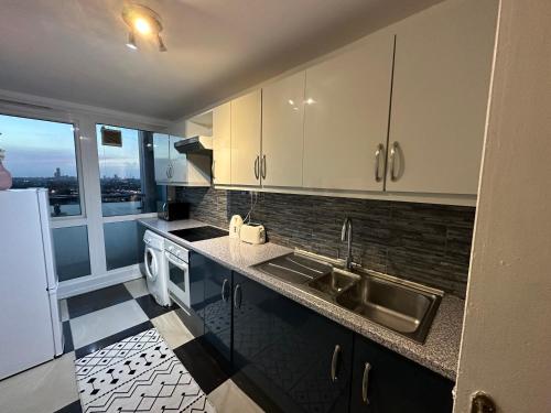 a kitchen with white cabinets and a sink and a refrigerator at Flat near Business Bay Metro Station in Dubai in Dubai