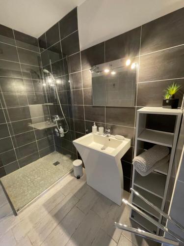 une salle de bain avec un lavabo blanc et une douche dans l'établissement Appartement T3 Terrasse Vue Mer Bandol, à Bandol