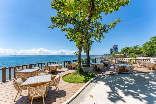 a patio with tables and chairs next to the water at Relaxing SEA VIEW condo Mactan Newtown in Punta Engaño