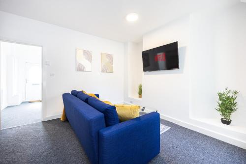 a living room with a blue couch and a tv at 4 beds home, 3 baths, sleeps 8, free parking, contractors, trades in Purfleet