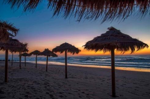 a group of umbrellas on a beach with the ocean at Romy suites Deluxe in Netanya
