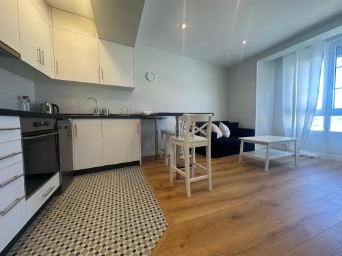 a kitchen with white cabinets and a table and a chair at Picasso in Culleredo