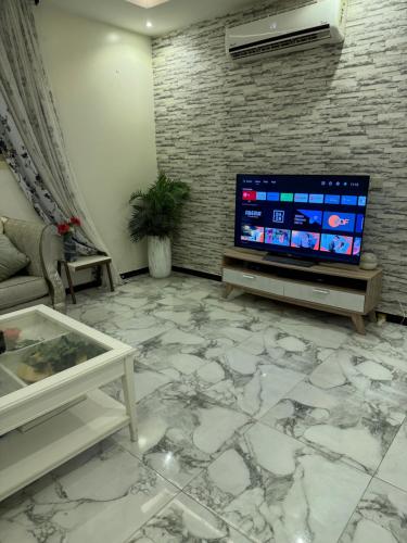 ein Wohnzimmer mit einem großen TV und Marmorboden in der Unterkunft شقة خاصة بغرفتي نوم ومطبخ وصالة ومجلس in Unaizah