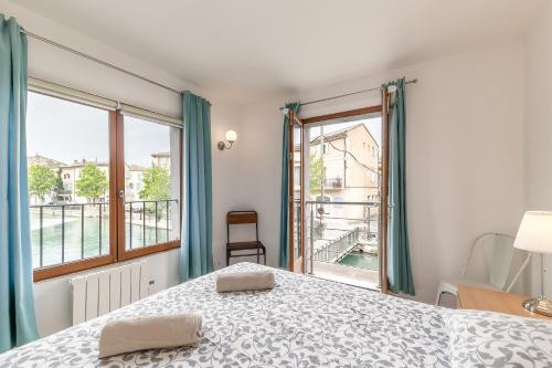 une chambre avec un lit et une grande fenêtre dans l'établissement Raisin- appartement familial donnant sur la Sorgue, à LʼIsle-sur-la-Sorgue