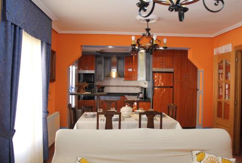 a kitchen with orange walls and a table and chairs at La Cuadra I in La Pola de Gordón