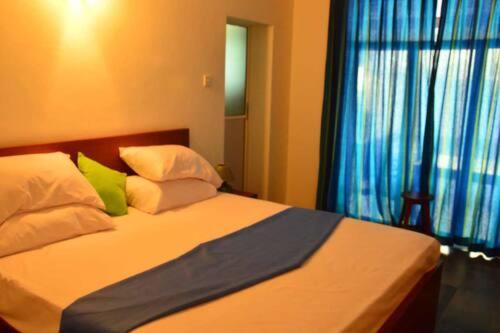1 dormitorio con 1 cama con almohadas blancas y verdes en Fernando viila, en Wadduwa
