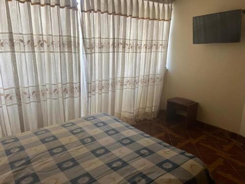 a bedroom with a bed and a window with curtains at HOTEL ARC&SUITE in Tacna