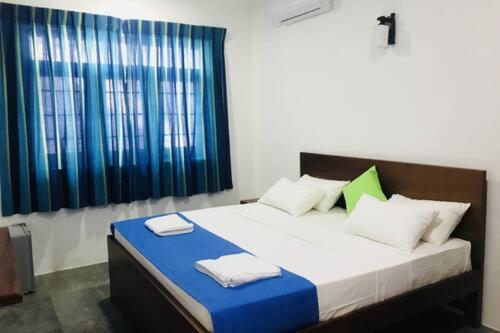 1 dormitorio con 1 cama grande con almohadas azules y blancas en Fernando viila, en Wadduwa