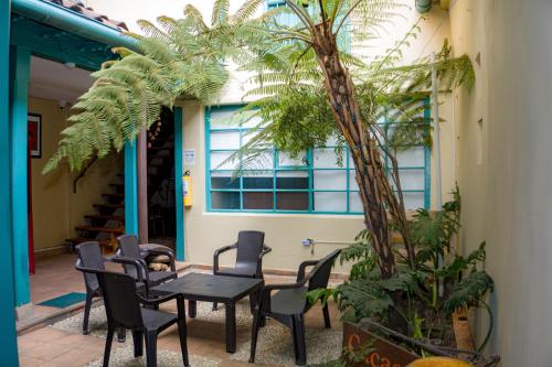 a patio with a table and chairs and a palm tree at By Cao Rest House in Bogotá