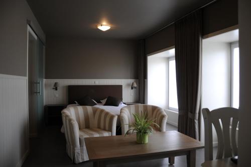 a bedroom with a bed and a table and chairs at Kapelhoeve in De Haan