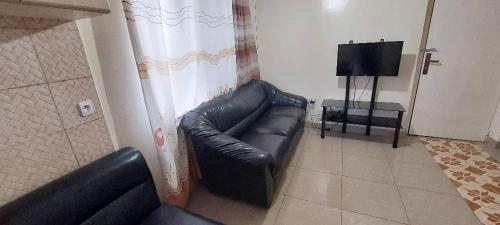 a black leather couch in a living room with a television at Home sweet home in Kigali