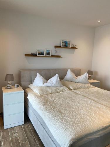 a bedroom with a large bed with a nightstand and a bed sidx sidx sidx at Moderne Ferienwohnung Meerestraum in Dangast in Varel