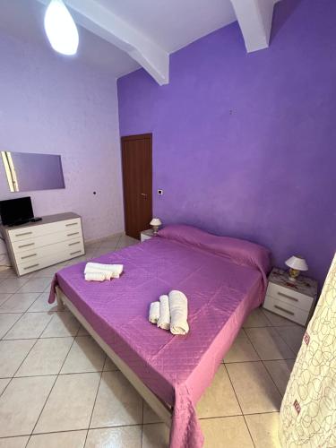 um quarto com uma cama roxa com toalhas em CasArcobaleno Fronte Policlinico em Messina
