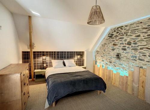 une chambre avec un lit et un mur en pierre dans l'établissement Gite de groupe Les KerChouers, à Lingreville