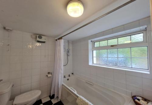 uma casa de banho com uma banheira, um WC e uma janela. em Cushatrough Claddaghduff em Claddaghduff