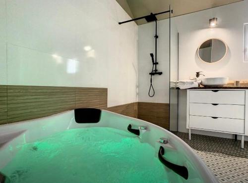 La salle de bains est pourvue d'une baignoire remplie d'eau verte. dans l'établissement Gite de groupe Les KerChouers, à Lingreville