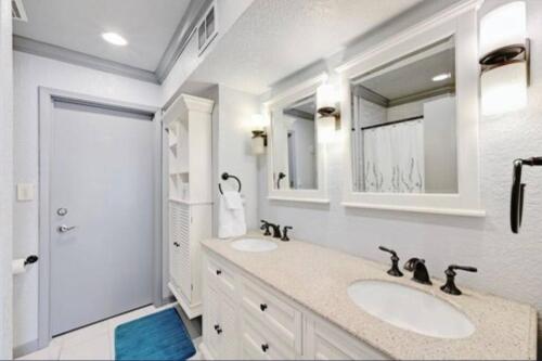a white bathroom with two sinks and a shower at Stunning Waterfront Property Sleeps 12+ in Horseshoe Bay