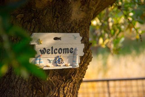 a welcome sign on a tree in a tree at Kroussos Cottage in Faraklata