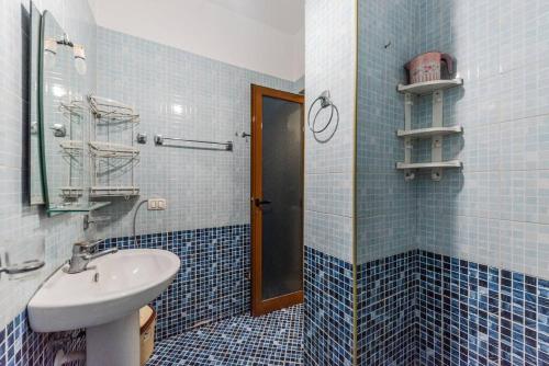 bagno piastrellato blu con lavandino e specchio di Cozy Seaside by PS a Golem