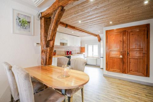 a dining room with a wooden table and a kitchen at Le Gîte de Jade in Dannemarie