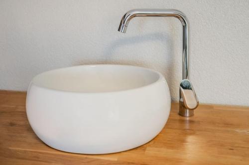 a white sink with a faucet on a wooden table at Le Gîte de Jade in Dannemarie