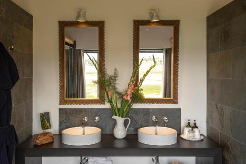 two sinks in a bathroom with two mirrors at Titilaka by Andean in Tililaca