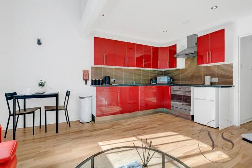 uma cozinha com armários vermelhos e uma mesa num quarto em Stylish Studio 5 - City Centre Coach Station em Birmingham