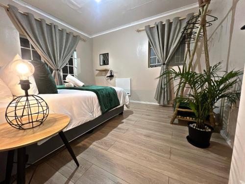 a bedroom with a bed and a table and plants at Lincoln Moon Guesthouse in Graskop