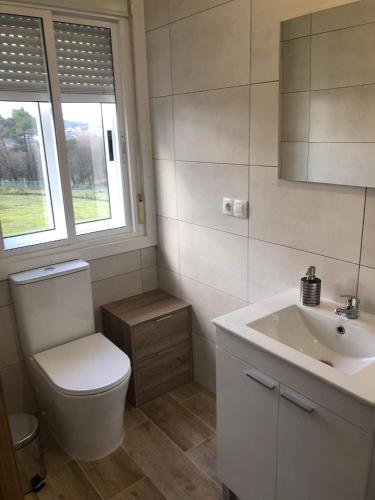 a bathroom with a toilet and a sink and a window at Casa Aricel VT in Chantada