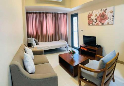 a living room with a couch and a tv and a bed at Relaxing SEA VIEW condo Mactan Newtown in Punta Engaño