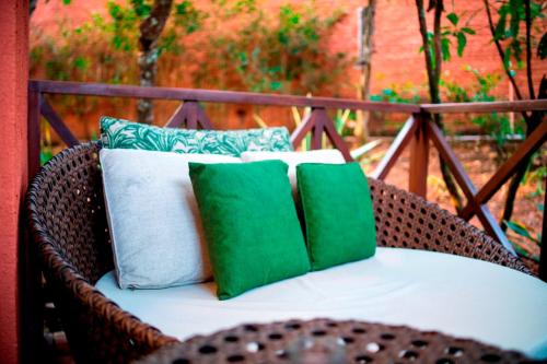 a wicker chair with four green and white pillows at Ananda Pousada in Pirenópolis