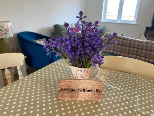 a vase of purple flowers sitting on a table at Bluebells, Little Snoring in Fakenham