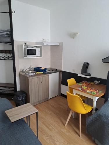 a small kitchen with a table and yellow chairs at Ludotel in Belley