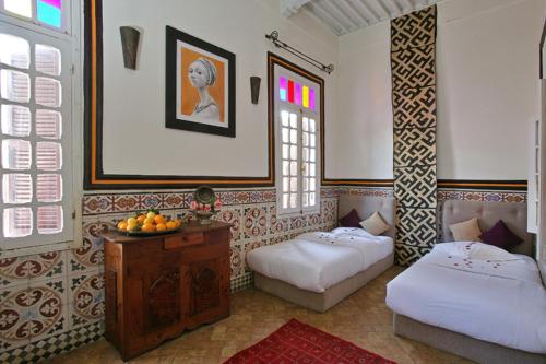 een kamer met twee bedden en een tafel met fruit erop bij Casa Lila & Spa in Essaouira