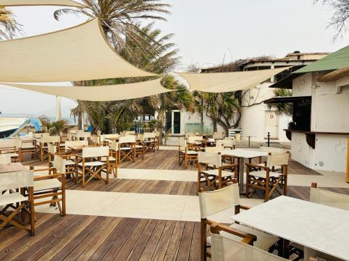 a restaurant with tables and chairs on a deck at Lido Di Alghero Rooms on the Beach in Alghero