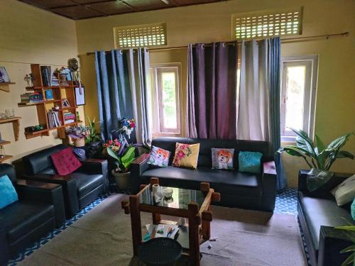 K Swu Homestay في Kohīma: غرفة معيشة مع أرائك سوداء ووسائد ملونة