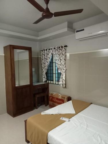 a bedroom with a bed and a window and a ceiling fan at Jalaliyaa residency in Cochin
