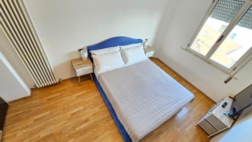 een slaapkamer met een bed met een blauw hoofdeinde en een raam bij Happy House - Marina Centro in Rimini