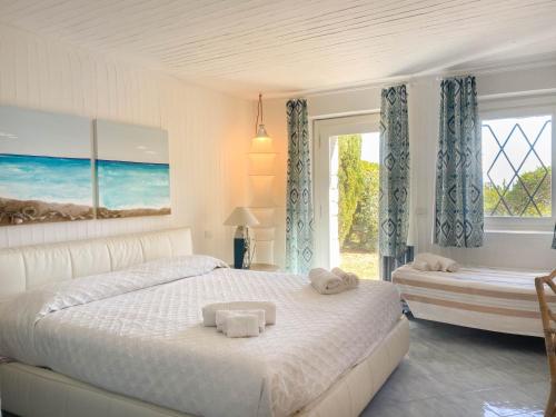 a white bedroom with a bed and a window at BGItalianVacation - Ville Li Conchi in Castiadas
