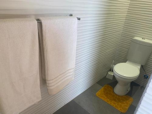 a bathroom with a white toilet and towels at GOLDEN GLORY INN in Roodepoort