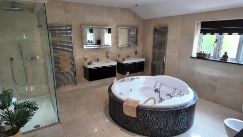 uma casa de banho com uma banheira, 2 lavatórios e um chuveiro em Stratford-upon-Avon Family Mansion em Henley in Arden