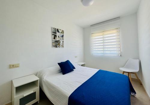een witte slaapkamer met een blauw bed en een raam bij BOOK MEDITERRANI CAMBRILS in Cambrils