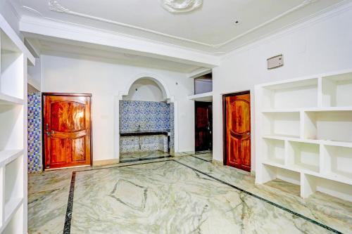 ブバネーシュワルにあるSuper OYO Flagship Namaskar Cozzy Cottageの白い壁と木製のドアが特徴の広い客室です。