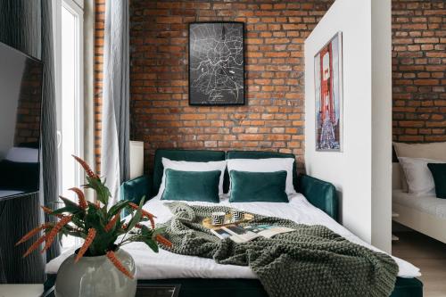 - une chambre avec un lit vert et un mur en briques dans l'établissement Rotunda Apartment by LoftAffair, à Cracovie