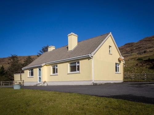 a yellow house with a hill in the background at Lough Fee Renvyle in Renvyle