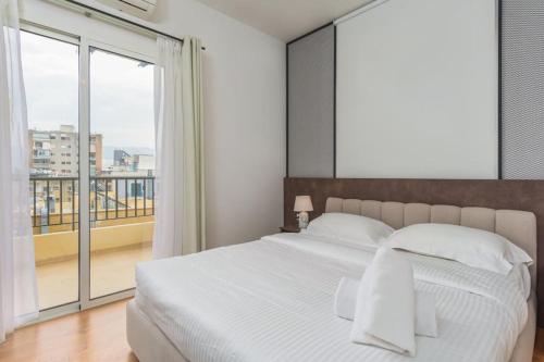 a bedroom with a white bed and a large window at Alice 2-BR in Mar Mikhael in Beirut